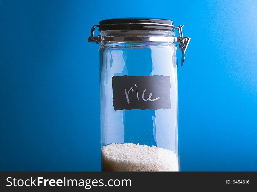 Inscription Rice on transparent glass jar. Over blue background