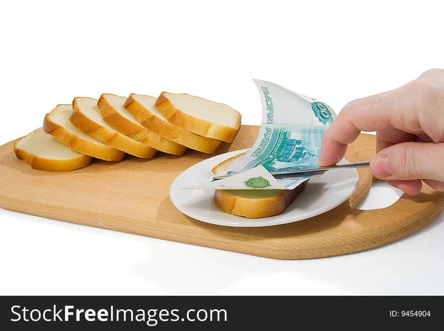 Hand spreads bread with thousand-roube banknote on small plate on chopping board. Hand spreads bread with thousand-roube banknote on small plate on chopping board