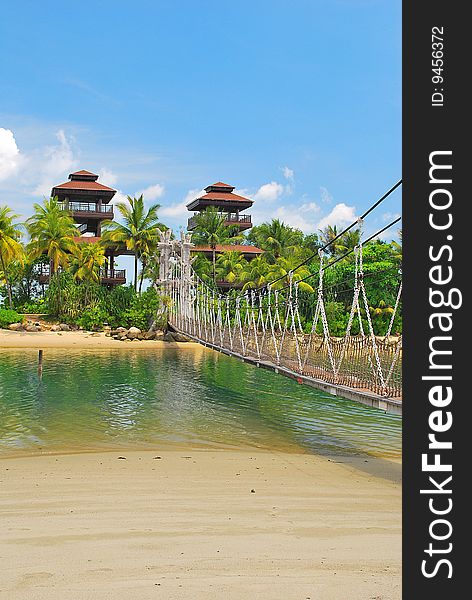 Wooden suspension bridge leading to paradise island, with hotels in the background. Wooden suspension bridge leading to paradise island, with hotels in the background