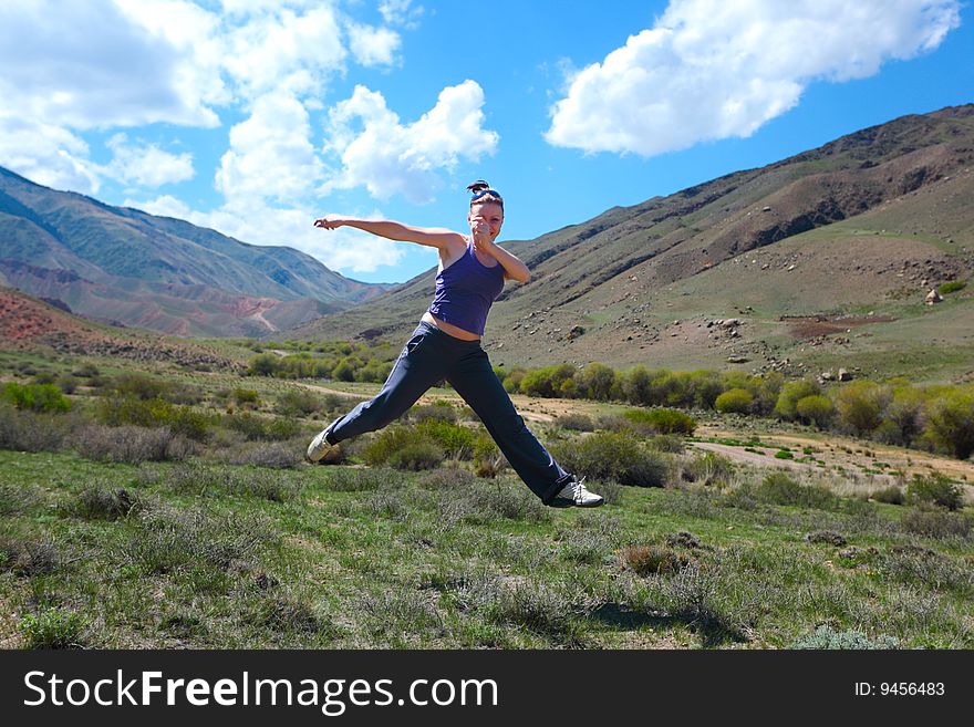The girl jumping upwards against mountains. The girl jumping upwards against mountains