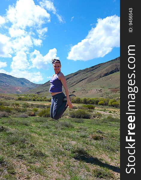 The girl jumping upwards against mountains. The girl jumping upwards against mountains