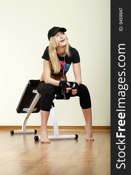 Smiling girl in cap sitting on fitness machine. Smiling girl in cap sitting on fitness machine