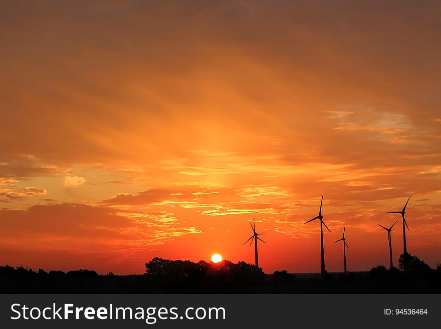 Wind turbines silhouetted in the sunset.