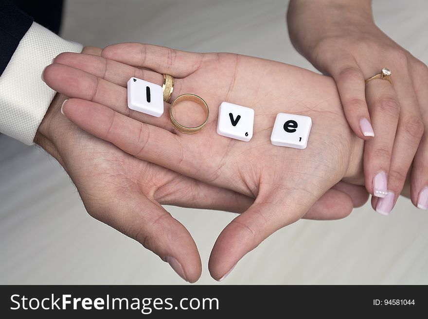 The hands of a couple with the word "love" written on with letter tiles. The hands of a couple with the word "love" written on with letter tiles.