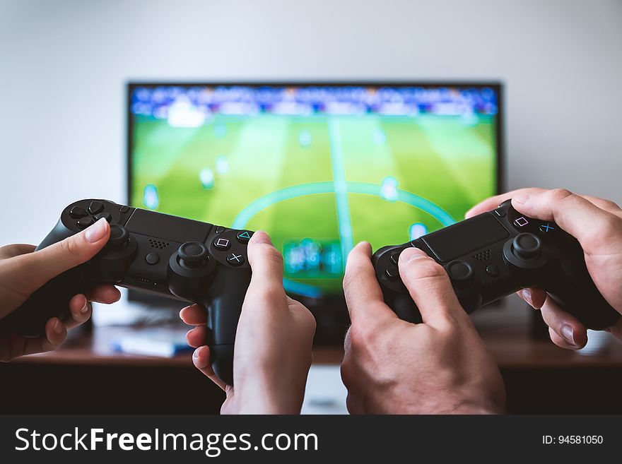 A close up of hands holding gamepads playing a video game.