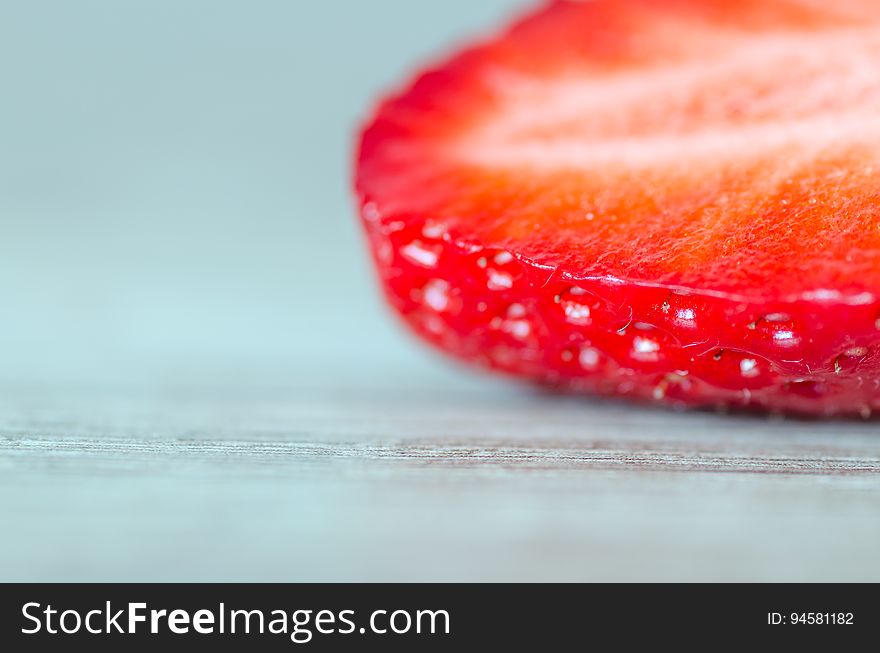 A slice of a strawberry fruit on wood background. A slice of a strawberry fruit on wood background.