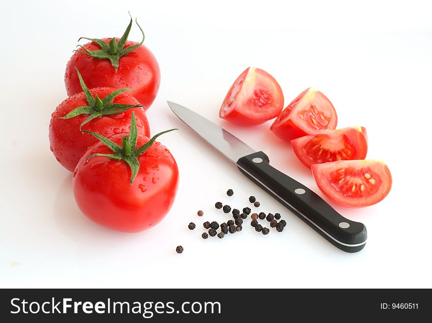 A close-up picture of fresh tomatos with water drops, pepper and knife. A close-up picture of fresh tomatos with water drops, pepper and knife