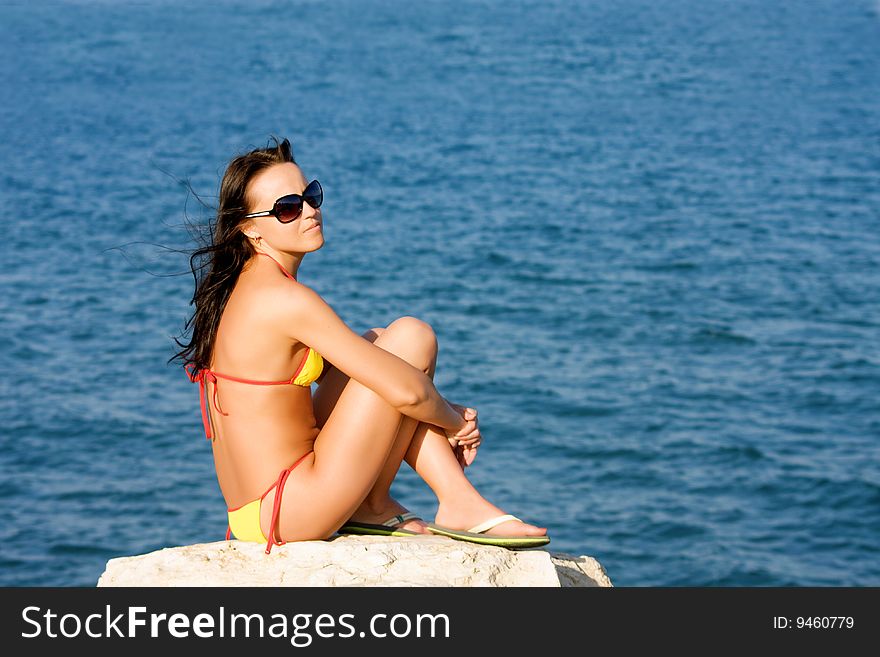 Girl sits on the beach of the blue sea
