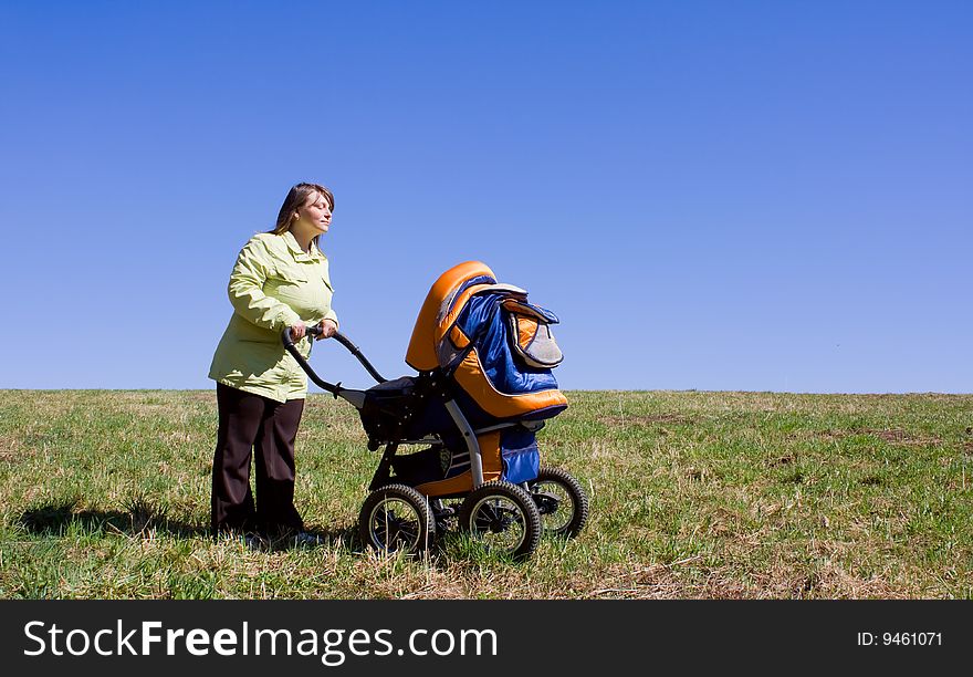 The girl with a children carriage in a field. The girl with a children carriage in a field