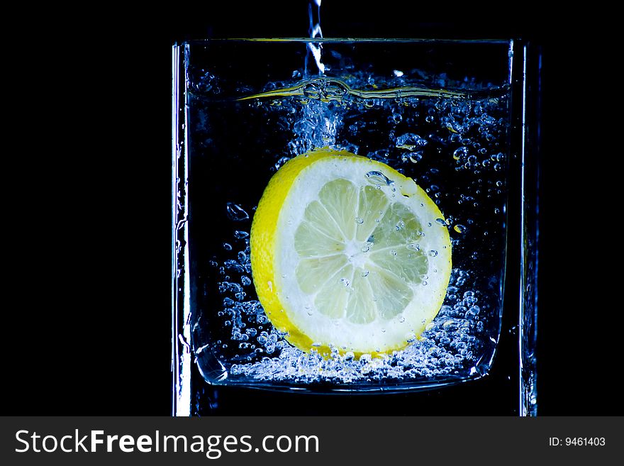 Citron flows into glass of water. Citron flows into glass of water