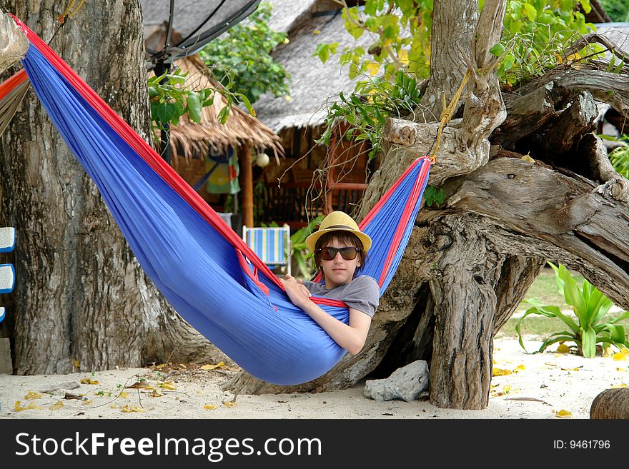 Boy in a hat and sunglasses in a blue hammock