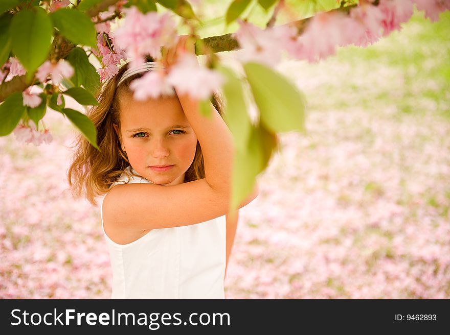 Pretty little girl posing on a a lawn that's covered with rosey petals. Pretty little girl posing on a a lawn that's covered with rosey petals