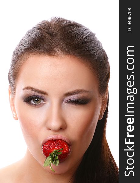 Sexy young woman holding strawberry in her mouth and winking. Sexy young woman holding strawberry in her mouth and winking