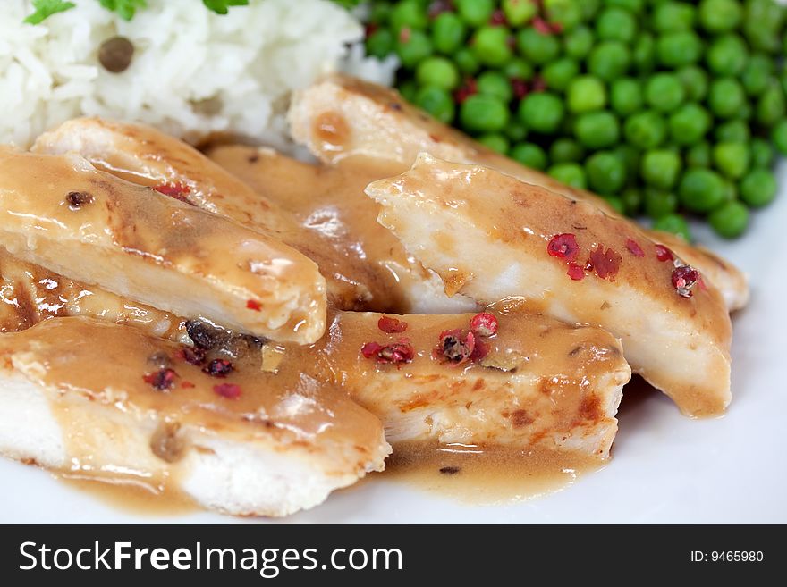 Grilled slices of turkey meat with green pea and rice.