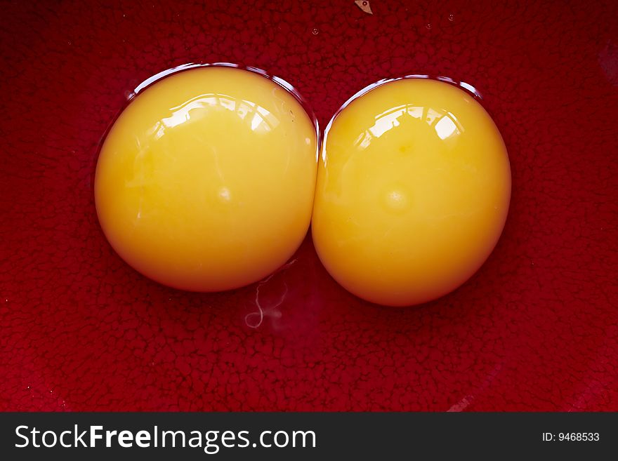 One cracked open raw egg with two yellow yolks. One cracked open raw egg with two yellow yolks.
