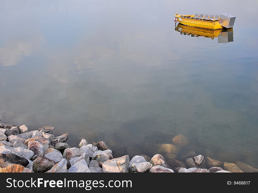 Isolated yellow boat with jugged rocks in the foreground. Isolated yellow boat with jugged rocks in the foreground