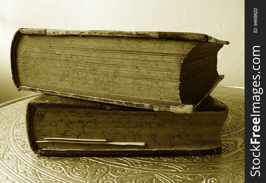 Two old books on a table in sepia