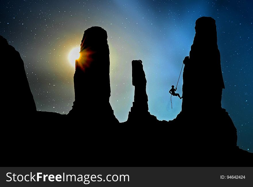 Silhouetted rocks and a cliff climber at dusk. Silhouetted rocks and a cliff climber at dusk.