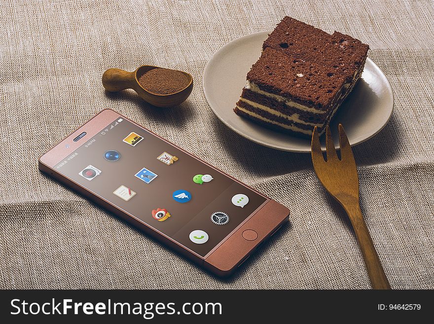 A piece of chocolate cake and a chocolate colored mobile phone. A piece of chocolate cake and a chocolate colored mobile phone.