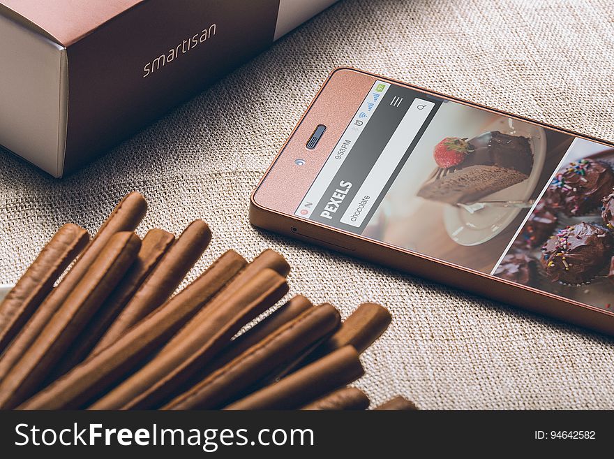 A chocolate colored smartphone and chocolate sticks on burlap background. A chocolate colored smartphone and chocolate sticks on burlap background.