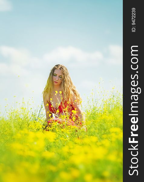 beautiful woman sitting between yellow flowers. beautiful woman sitting between yellow flowers