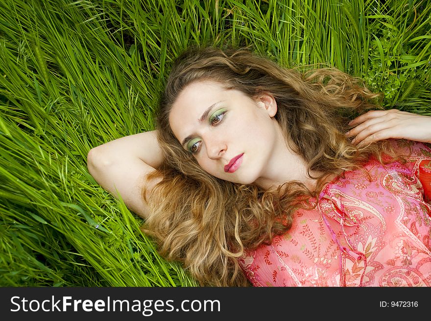 Beautiful woman lying on green grass relaxing in summer. Beautiful woman lying on green grass relaxing in summer