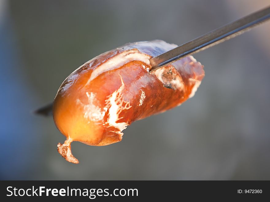 Preparation of a juicy sausage on a fire and a skewer