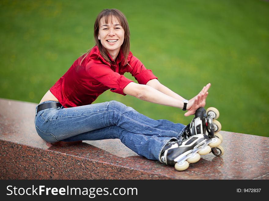 Rollerskating girl in blue jeans sitting on granite plate - shallow DOF