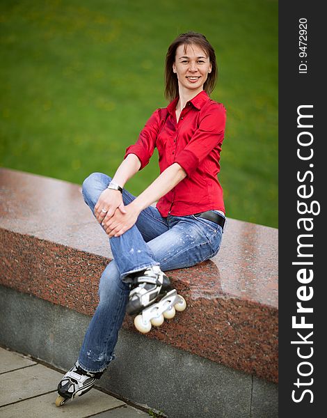 Rollerskating girl in blue jeans sitting on granite plate - shallow DOF