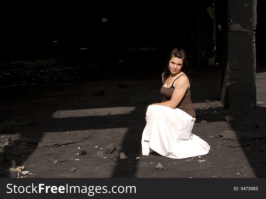 Young woman in a white dress, in an old black factory. Young woman in a white dress, in an old black factory