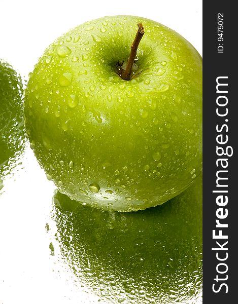 Fresh green apple with water drops on a mirror