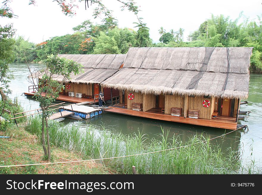 A row of small wooden huts on a clean river in the Kanchanaburai Province of Thailand. A row of small wooden huts on a clean river in the Kanchanaburai Province of Thailand.