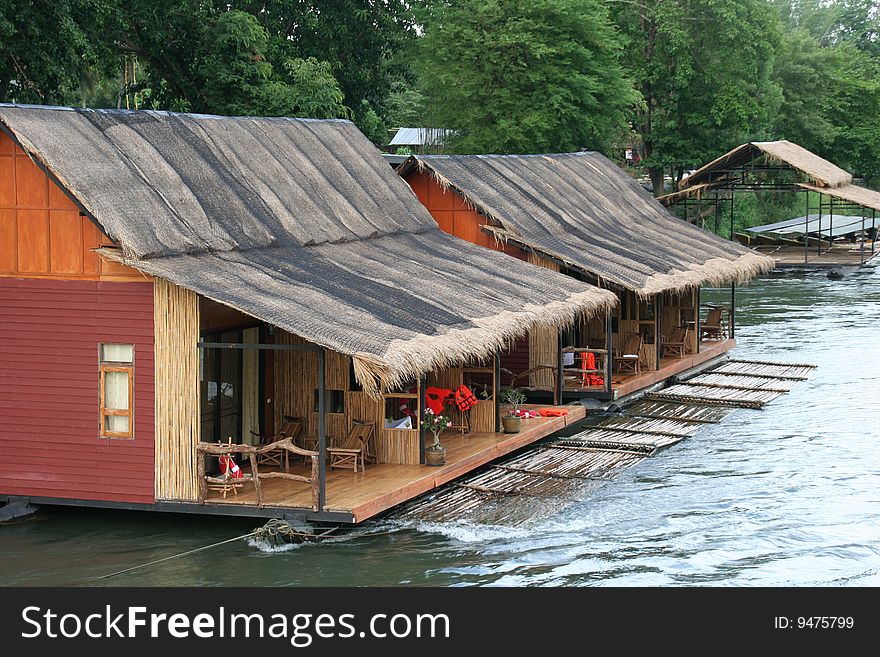 A row of small wooden huts on a clean river in the Kanchanaburai Province of Thailand. A row of small wooden huts on a clean river in the Kanchanaburai Province of Thailand.