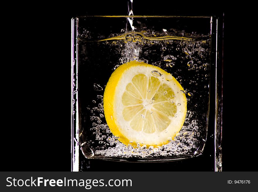 Citron flows into glass of water. Citron flows into glass of water