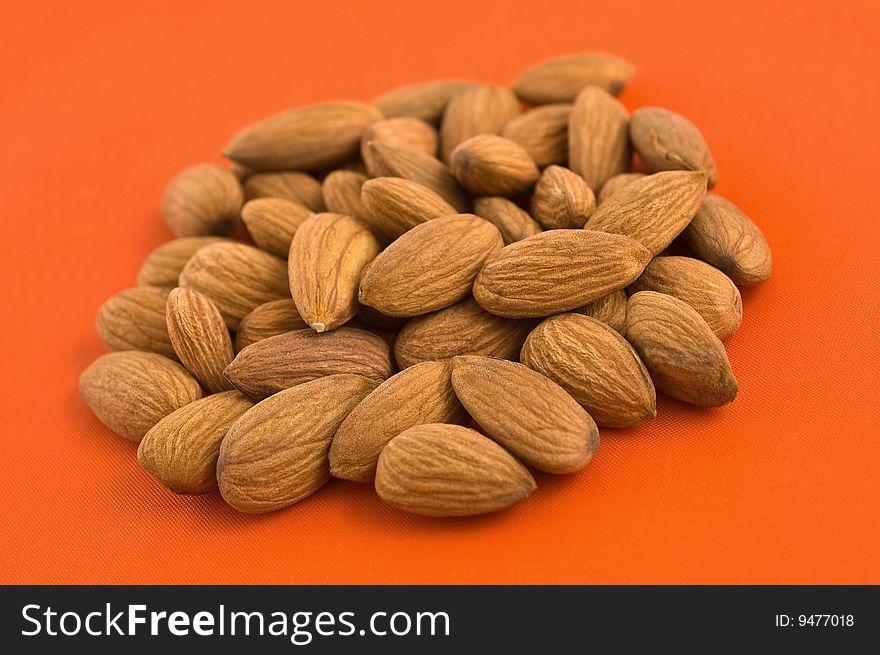 Group of almond kernels on orange background. Group of almond kernels on orange background.