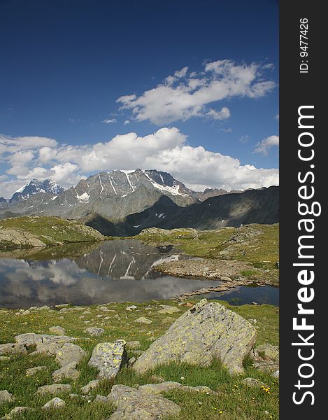 A mountain lake on the Swiss/Italian border, under a blue sky with light cloud. A mountain lake on the Swiss/Italian border, under a blue sky with light cloud.