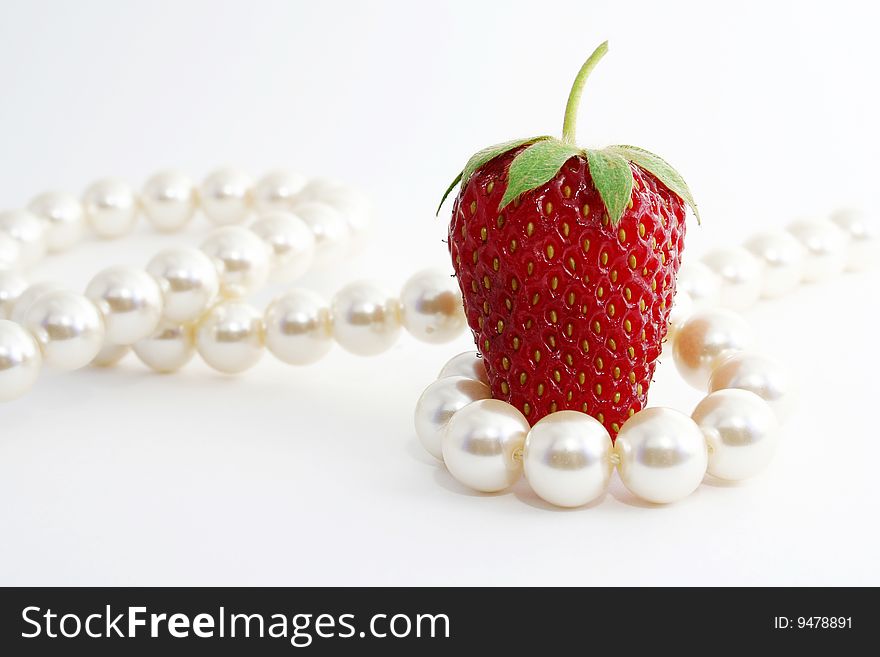 The Berries of the ripe strawberries and pearl necklace on white background. The Berries of the ripe strawberries and pearl necklace on white background.