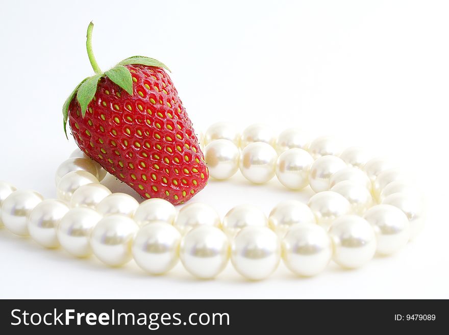 The Berries of the ripe strawberries and pearl necklace on white background. The Berries of the ripe strawberries and pearl necklace on white background.