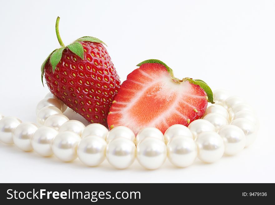 The Berries of the ripe strawberries and pearl necklace on white background. The Berries of the ripe strawberries and pearl necklace on white background.