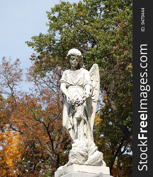 Sculpture of angel with fall trees in background. Sculpture of angel with fall trees in background