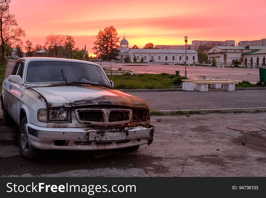 Burned car on sunset background