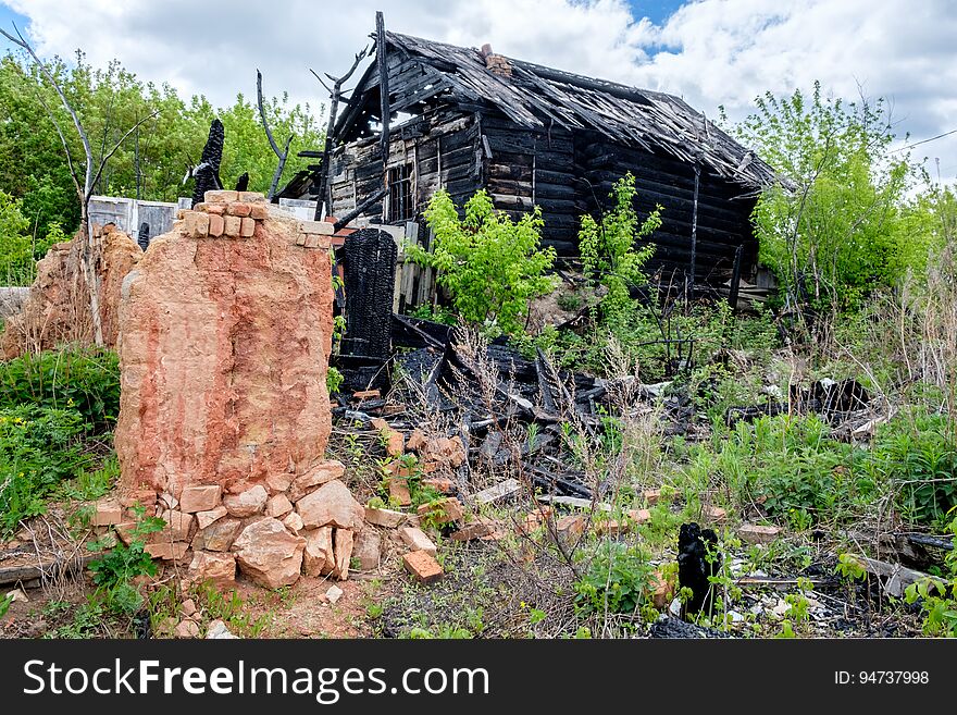 Wooden house after a fire on a background of green trees in the village