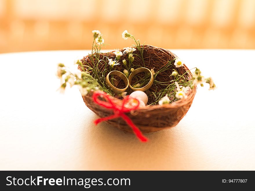Birds nest with gold rings and wildflowers on table with red bow. Birds nest with gold rings and wildflowers on table with red bow.