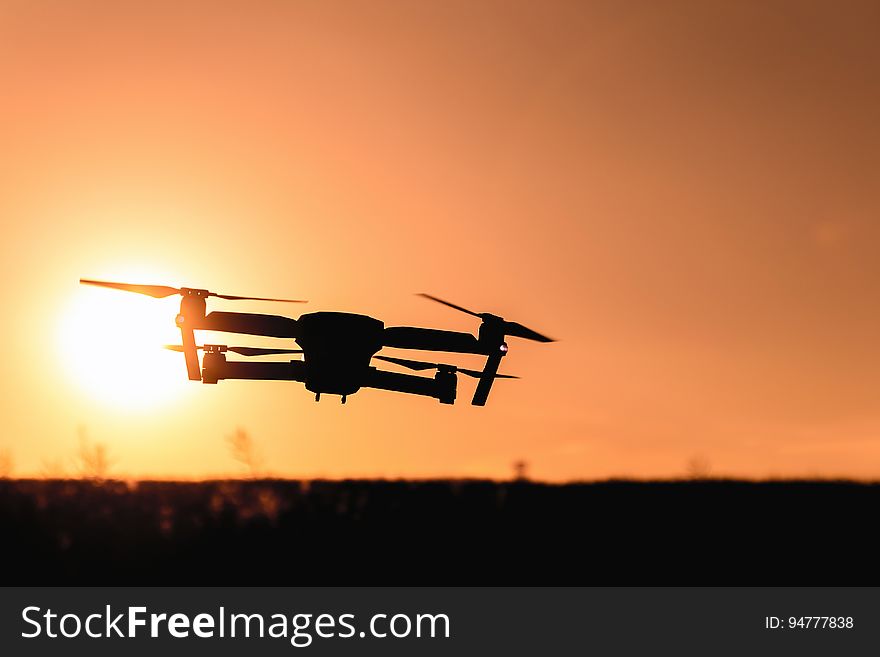 Quadcopter drone flying against setting sun. Quadcopter drone flying against setting sun.