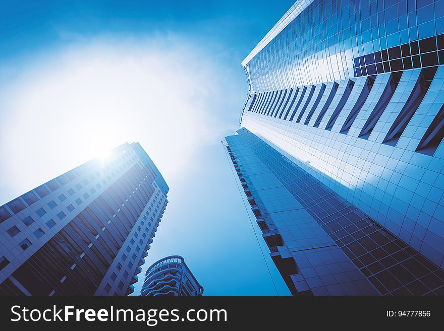 Abstract background created by skyscrapers of ultramodern architectural design and viewed upwards and into bright sunlight. Abstract background created by skyscrapers of ultramodern architectural design and viewed upwards and into bright sunlight.