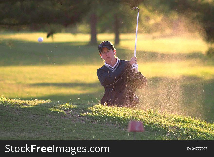 Golfer hitting out of sand trap on sunny course. Golfer hitting out of sand trap on sunny course.