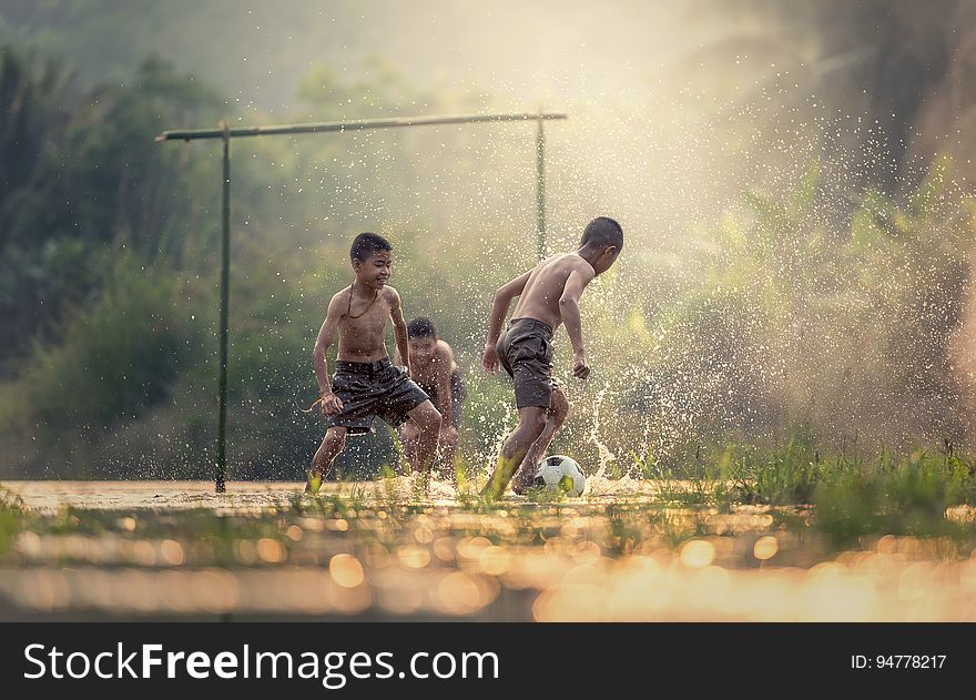Boys splashing while playing soccer in water on field. Boys splashing while playing soccer in water on field.