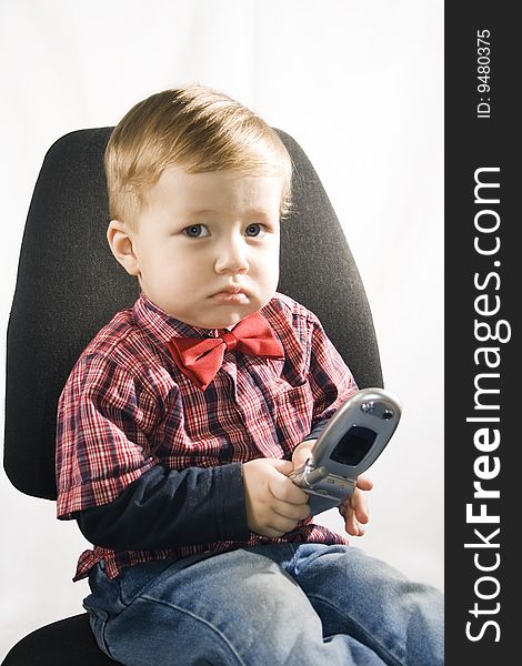 Little boy sitting in the armchair and the cell phone holds. Little boy sitting in the armchair and the cell phone holds