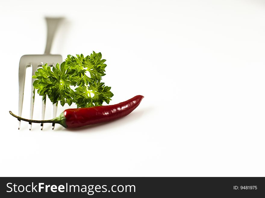 Fork with pepper and parsley over white background