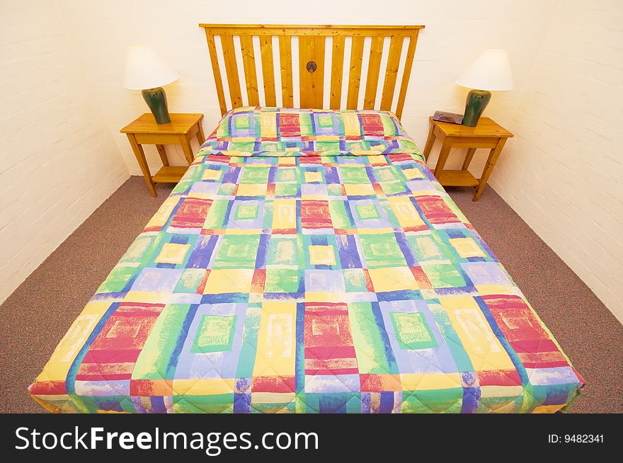 A queen sized bed in a room, decorated with two side tables and lamps. A queen sized bed in a room, decorated with two side tables and lamps.